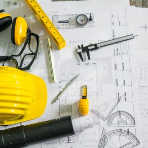 Construction plans with helmet and drawing tools on blueprints